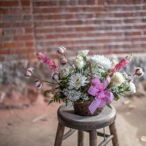 Basket arrangement of white and pink flowers with a gingham ribbon