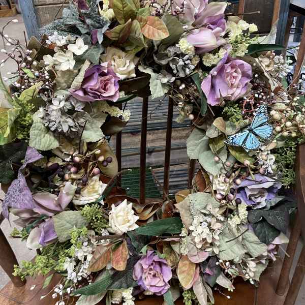 Floral wreath with purple and cream roses and a blue butterfly accent