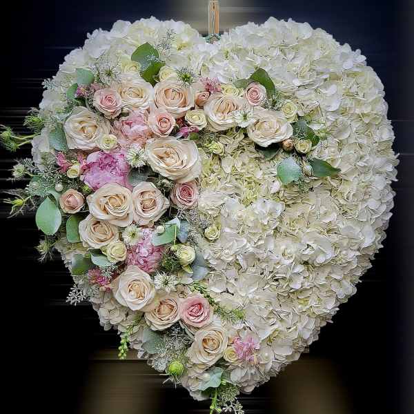 Heart-shaped white hydrangea wreath with cascading blush and pink roses.