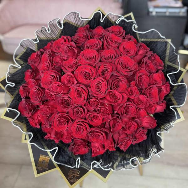 Large bouquet of red roses wrapped in black paper with gold accents