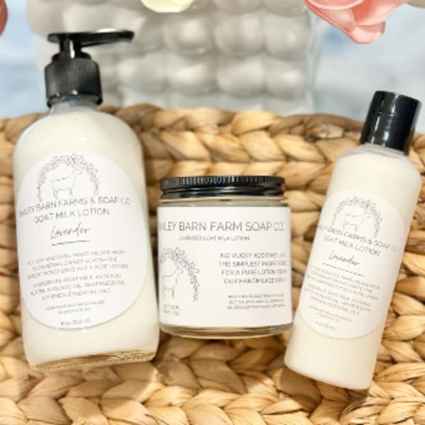 Gift set with lotion, soap, and a candle beside tulips in a woven basket