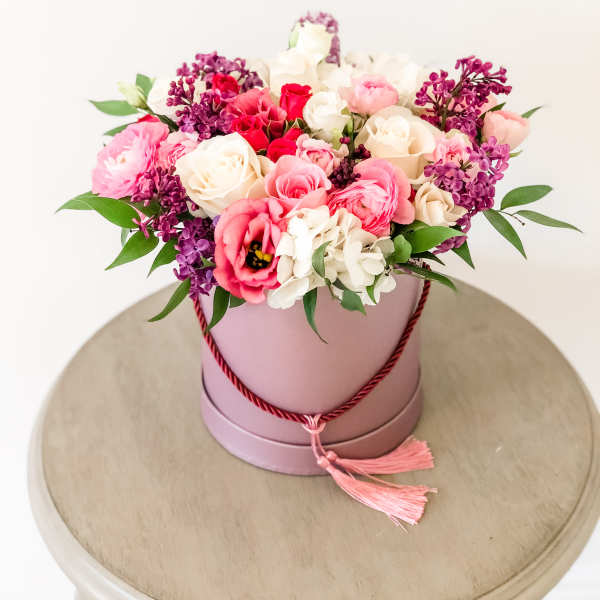 Pink and white rose arrangement in a round hatbox