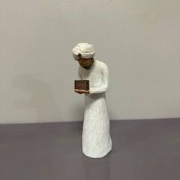 Small figurine in white robes holding a book