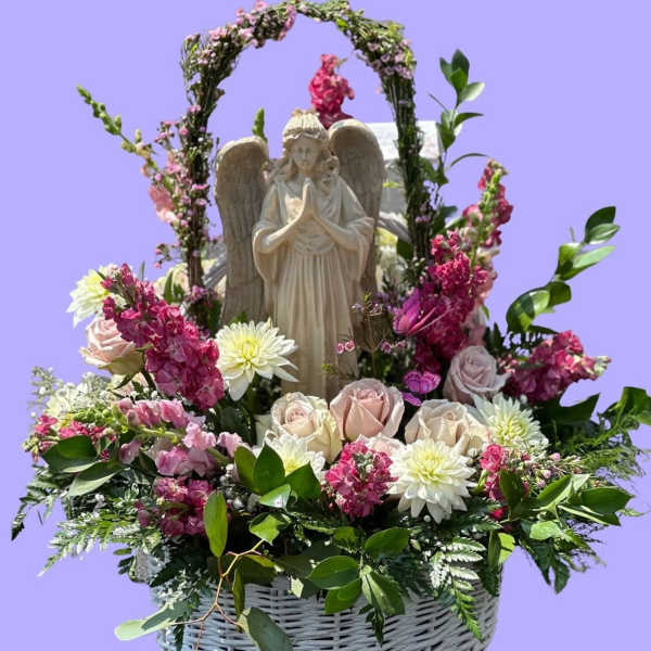 Basket arrangement with an angel statue, pink and white flowers, and greenery