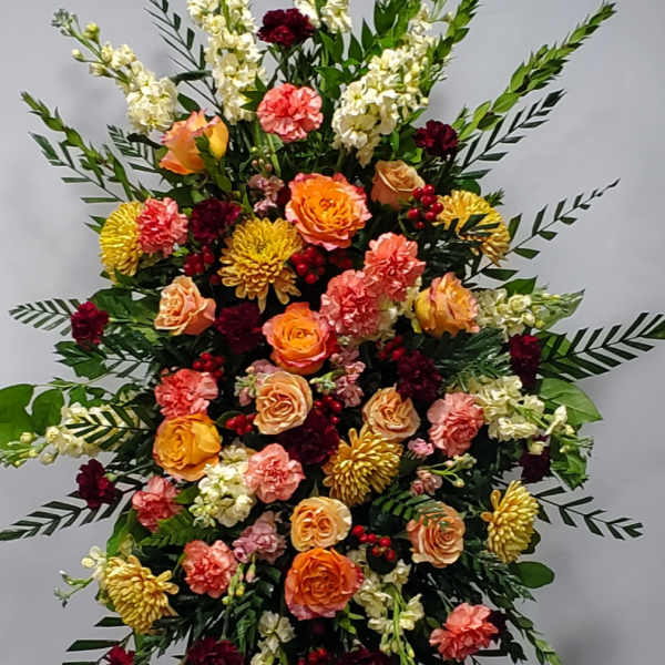 Large standing floral spray with roses, carnations, and white spikes