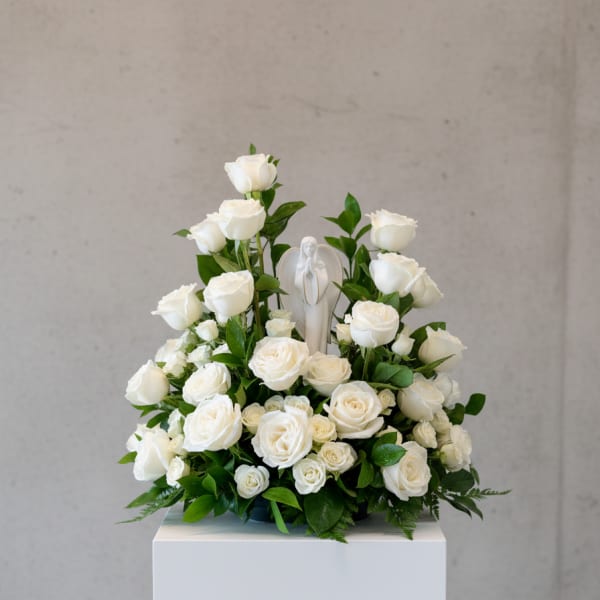 White rose arrangement with a small angel figurine in the center