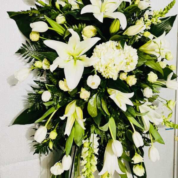 Large white funeral spray with lilies and tulips on a stand