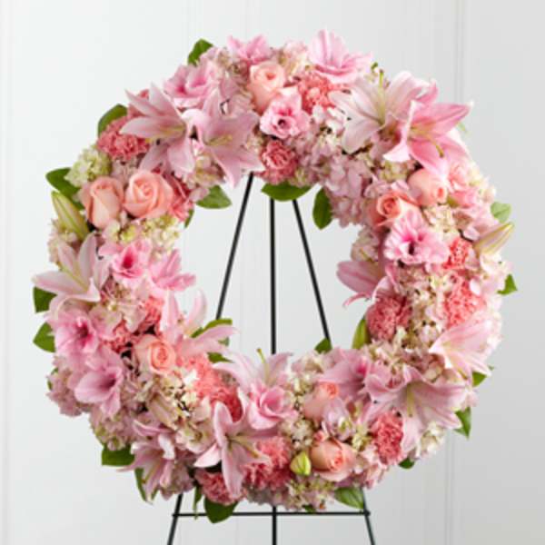 Pink floral wreath on a black metal stand