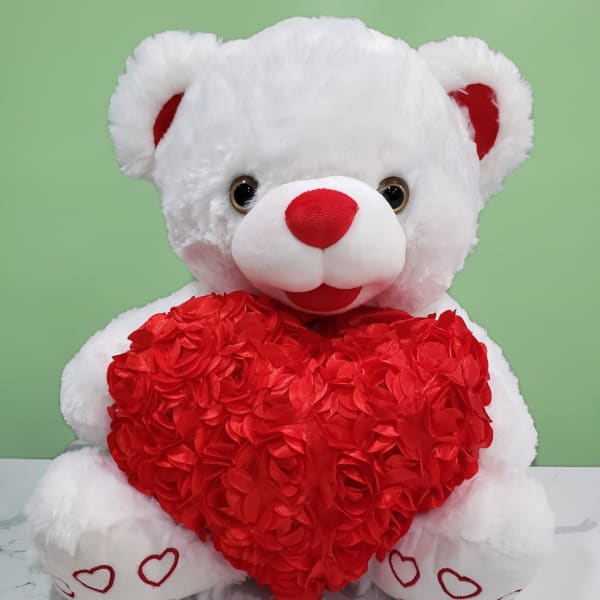 White teddy bear holding a red heart