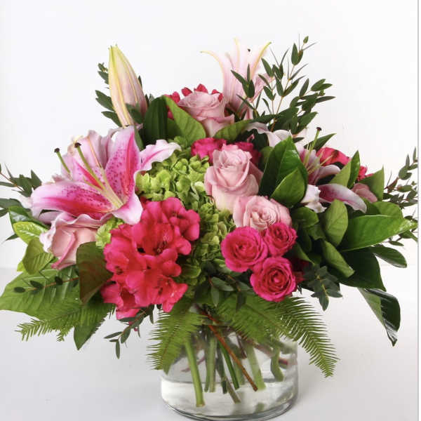 Pink lilies and roses arranged in a clear glass vase