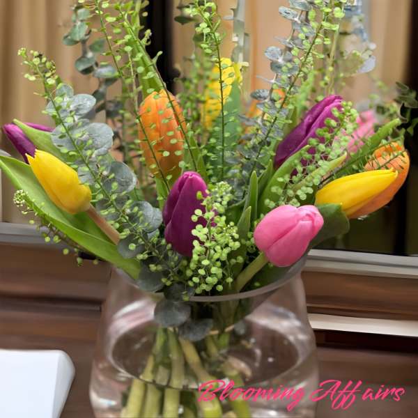 Colorful tulips arranged in a clear glass vase.