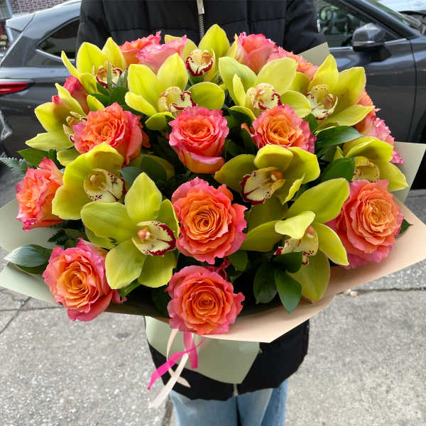Bouquet of coral roses and lime green orchids wrapped in paper