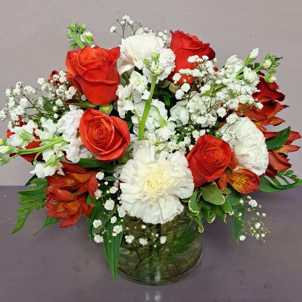 Red roses and white carnations in a glass vase with baby's breath