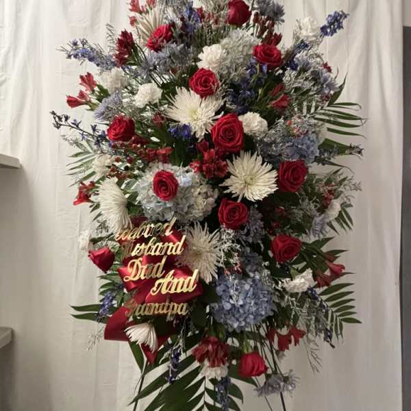 Large standing floral spray with red roses, white blooms, and blue flowers