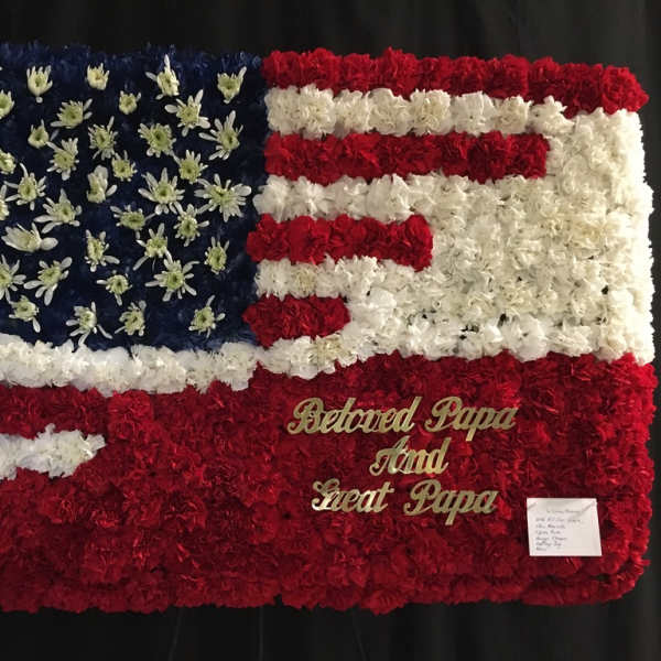 Floral tribute arranged as an American flag with red, white, and blue flowers.