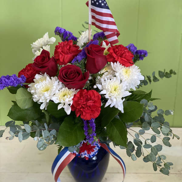 Red roses, white daisies, and carnations in a vase with an American flag