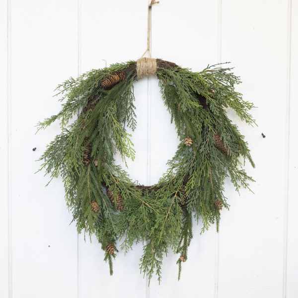 Evergreen wreath with pinecones hanging on a white door
