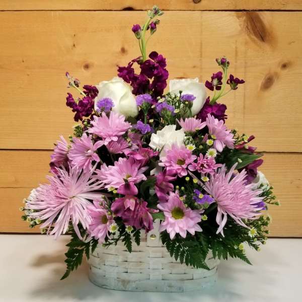 Pink and white mixed flowers arranged in a white basket