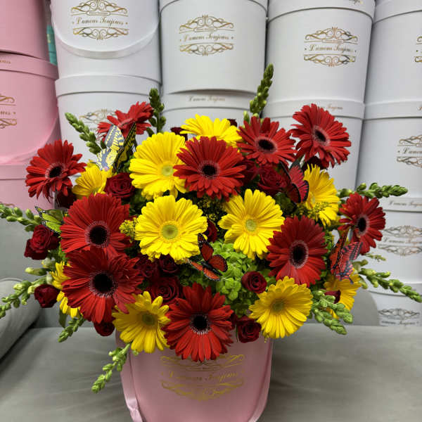 Bouquet of red and yellow daisies in a pink hatbox