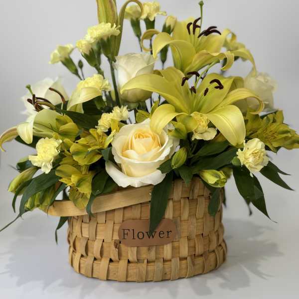 Yellow lilies and roses arranged in a woven basket