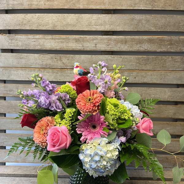 Mixed bouquet in a black vase with pink, purple, and coral flowers