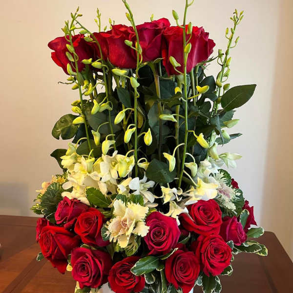 Tall red rose arrangement with white orchids in a white vase