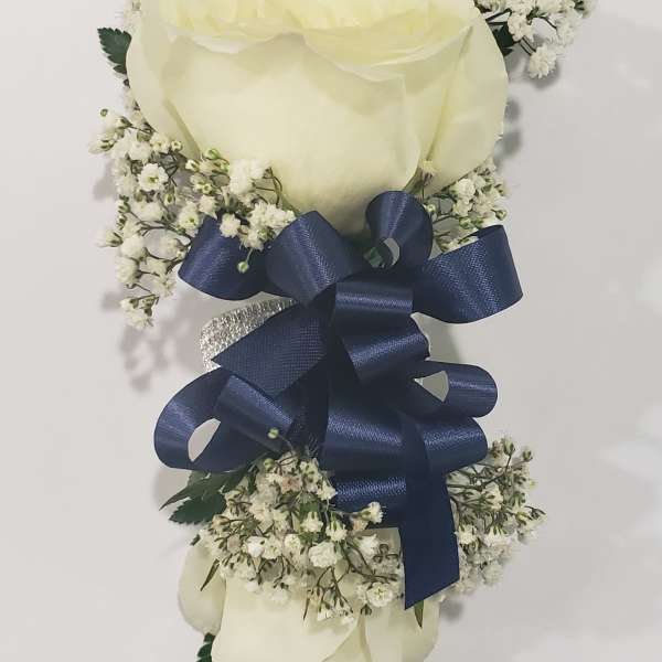 Three white roses with baby's breath and a navy ribbon