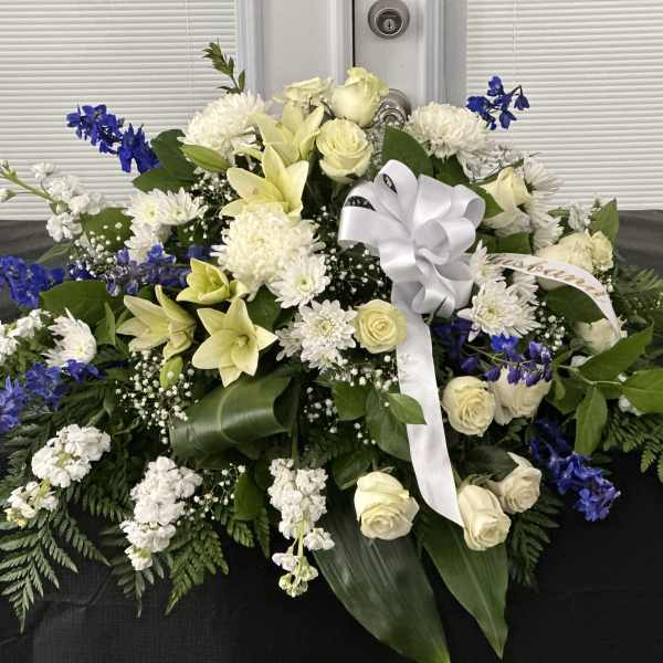 Large white and blue floral spray with a white ribbon bow