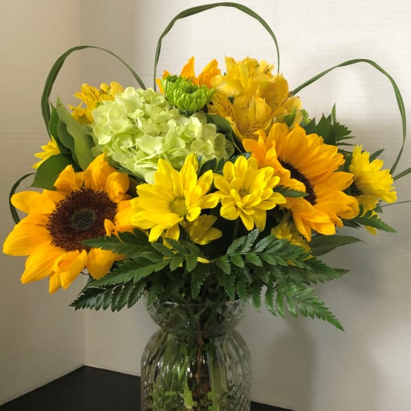 Sunflower and yellow mixed bouquet in a clear glass vase