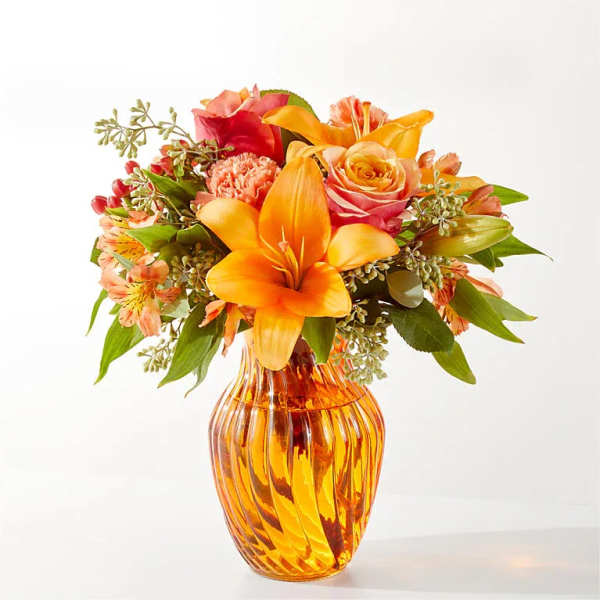Orange and pink mixed bouquet in an amber glass vase