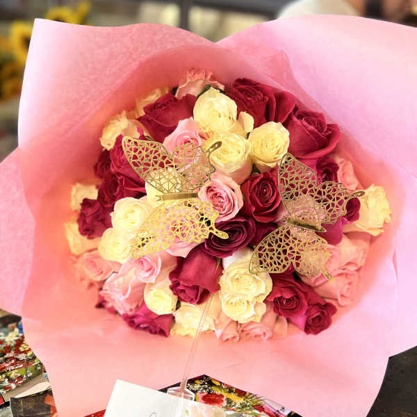 Bouquet of pink, red, and cream roses wrapped in pink paper