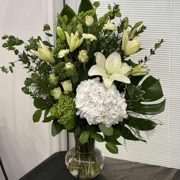 White lilies and hydrangea in a clear glass vase