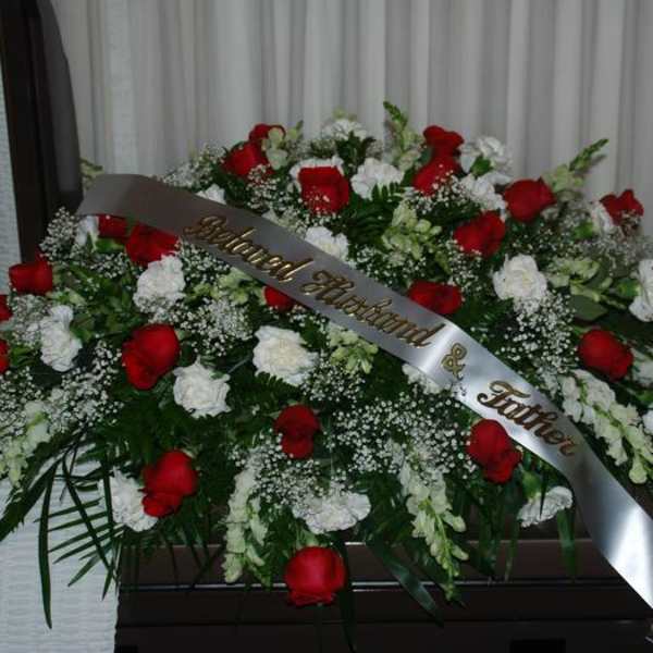 Large red and white rose funeral spray with a memorial ribbon
