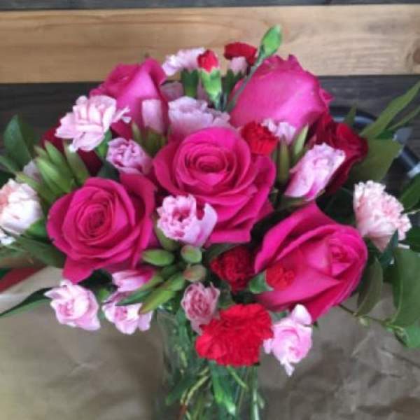 Arrangement of hot pink roses and pink and red carnations in a clear glass vase