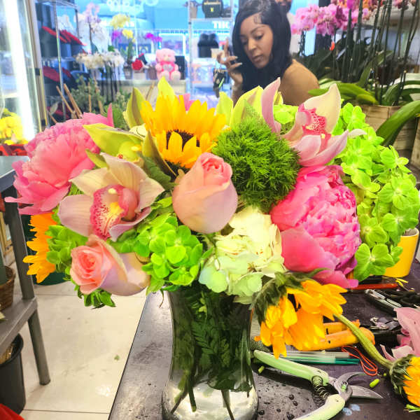 Bright mixed bouquet in a glass vase with pink, yellow, and green flowers