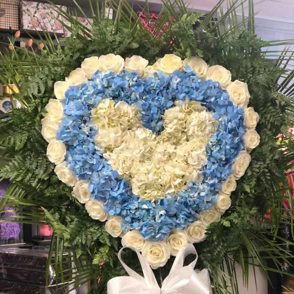 Heart-shaped floral wreath with blue hydrangeas and white roses, tied with a white bow