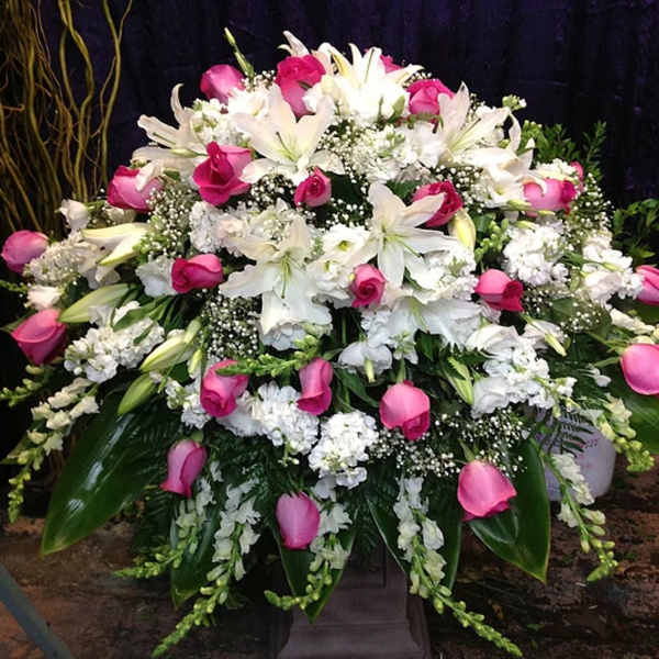 Large pedestal arrangement of white lilies and pink roses with white filler flowers.