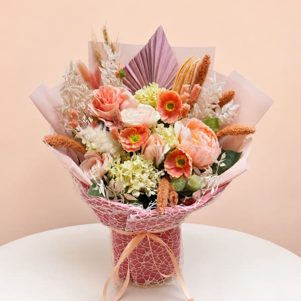 Peach and coral bouquet in pink wrap with ribbon