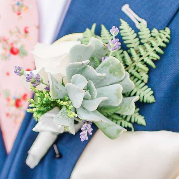 Boutonniere with pale succulent and lavender accents on a blue suit