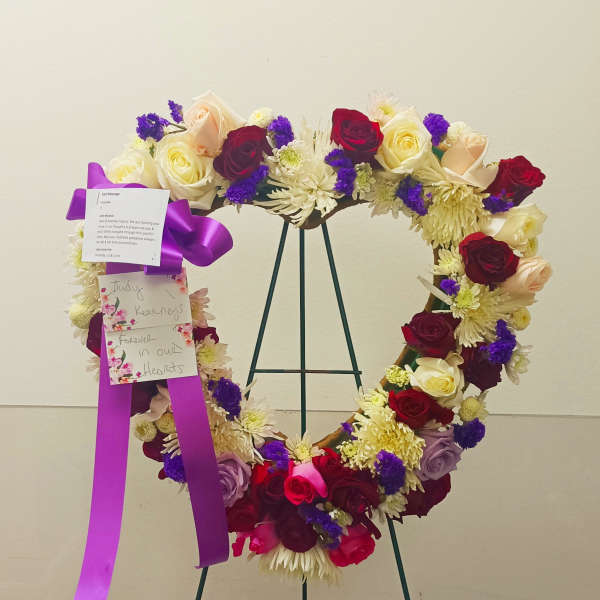 Heart-shaped floral wreath on a stand with roses and chrysanthemums