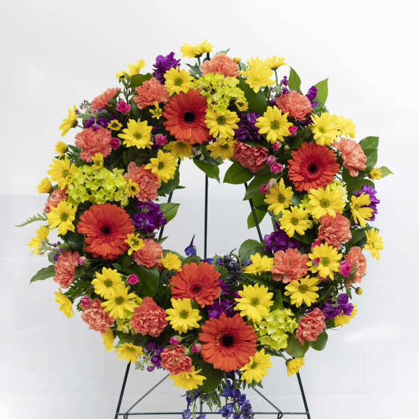 Colorful floral wreath on a metal stand with yellow, orange, purple, and pink blooms