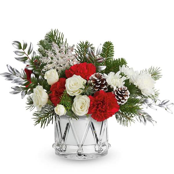 Red and white floral arrangement in a clear glass vase with pinecones