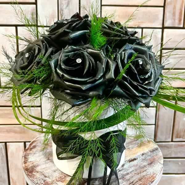 Black rose bouquet with green filler in a white vase