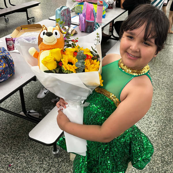 Child holding a bouquet of yellow flowers with a plush toy