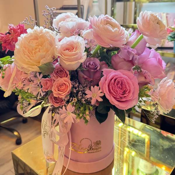 Pink and peach roses with ranunculus in a round pink box