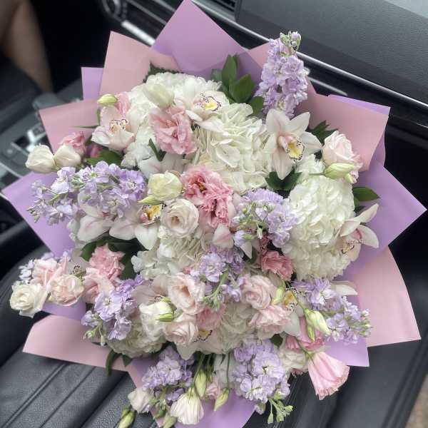 Bouquet of white and pale pink flowers wrapped in pink and lavender paper