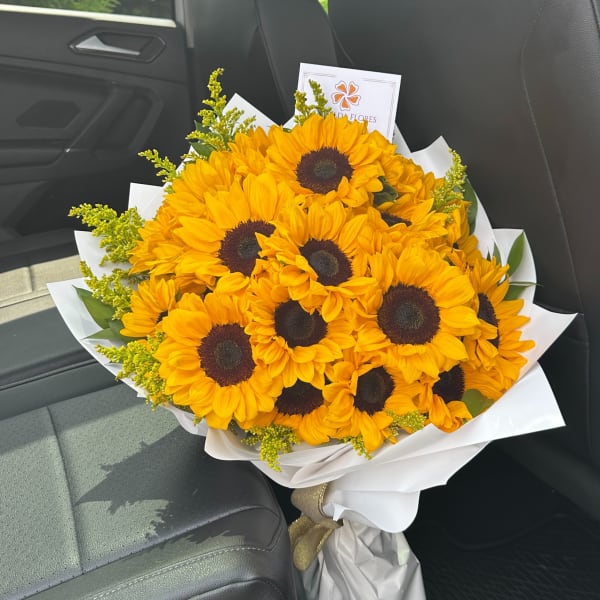 Bouquet of bright yellow sunflowers wrapped in white paper