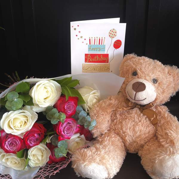 Bouquet of red, pink, and white roses with a teddy bear and birthday card