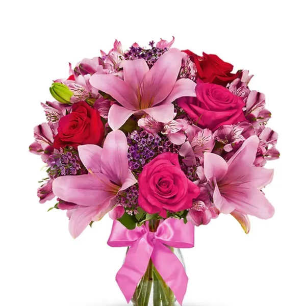Pink lilies and roses in a glass vase with a pink ribbon