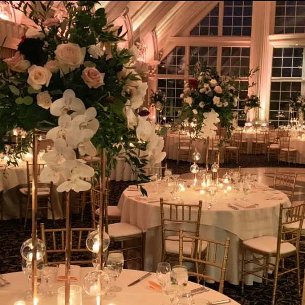 Tall floral centerpieces with white orchids and pale roses in a banquet hall
